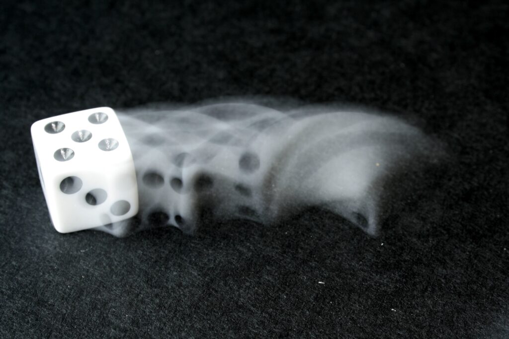 Белая игральная кость, катящаяся по столу